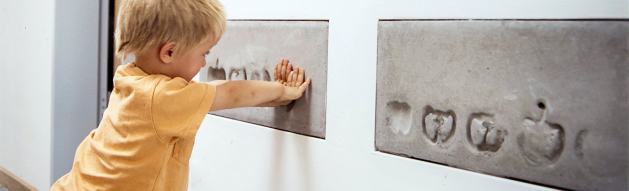 banner image, child pressing hands into cast shapes